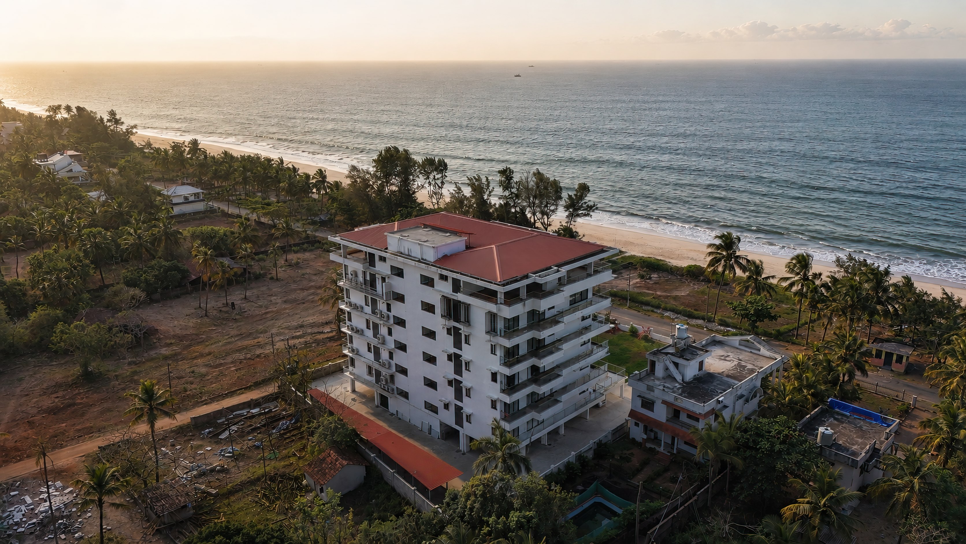 The beachfront building from above at sunset, with the sea and shoreline beyond